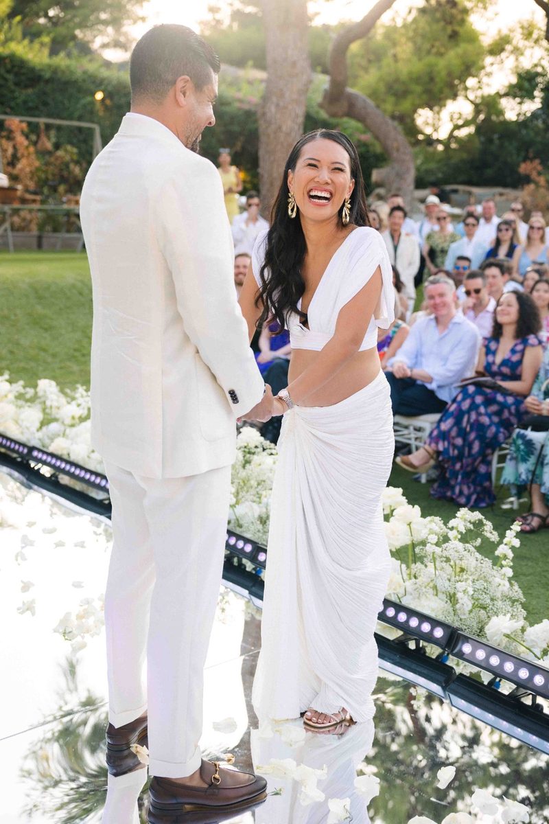 Bride laughing with her groom at an outdoor garden ceremony — wedding photography by John Xenos, Greece.