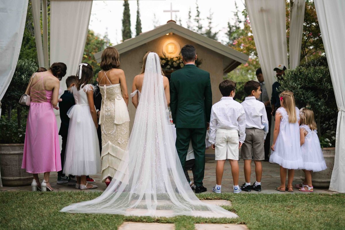 Wide view of a church ceremony with bride, groom and flower children — wedding photography by John Xenos, Greece.